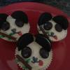Panda style vanilla cupcakes with white chocolate topping,Oreo ears, minstrel eyes, mikado bamboo(with green candy belts as leaves), red candy belt tongue, and icing nose.